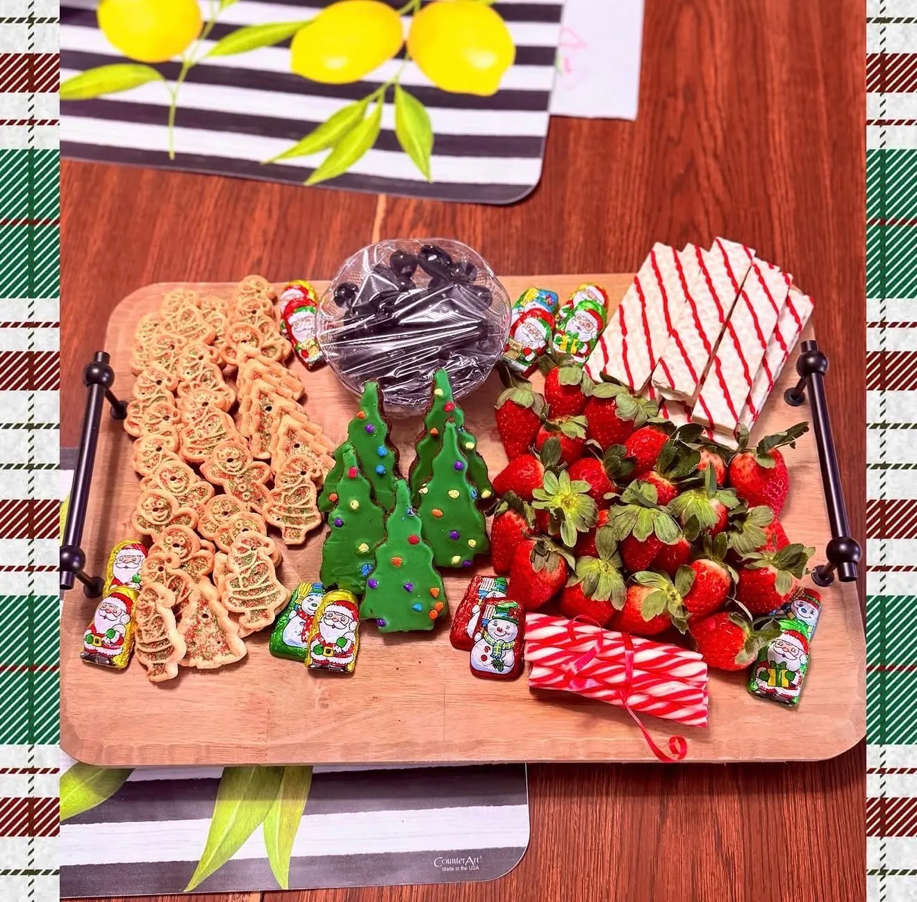 A holiday dessert grazing board with decorated gingerbread, chocolate-dipped strawberries, and Christmas-tree treats.